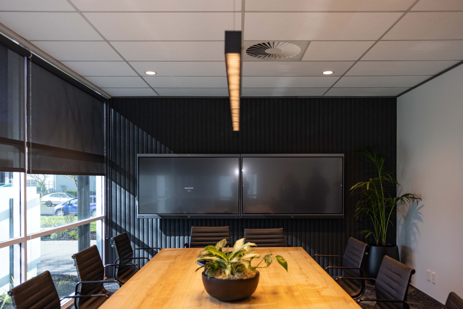 Boardroom with dark acoustic wall panels behind a long timber table