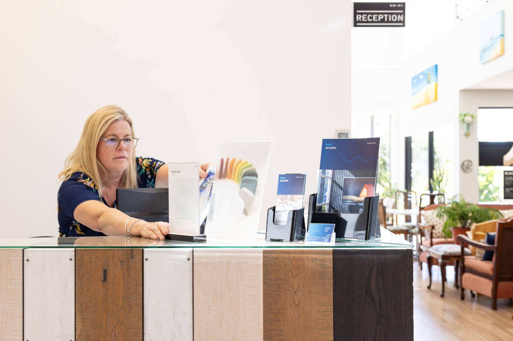 A woman at a reception counter with brochure holders and sign displays